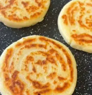 Golden arepas de queso on a griddle