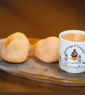 Two pandebonos beside a Recharge & Connect mug printed with the London skyline
